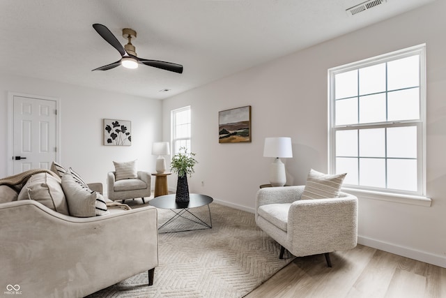 living area with visible vents, baseboards, ceiling fan, and wood finished floors