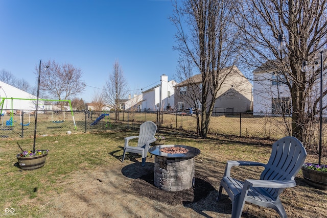 view of yard featuring a playground, fence, and an outdoor fire pit