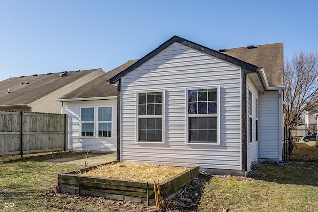 rear view of house with a yard, roof with shingles, and a fenced backyard