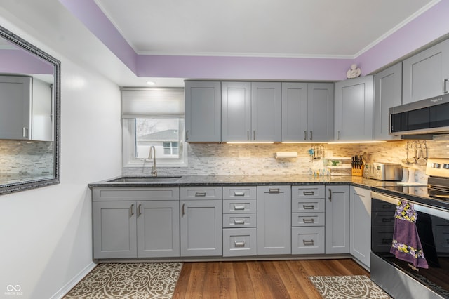 kitchen featuring a sink, tasteful backsplash, gray cabinets, and stainless steel appliances