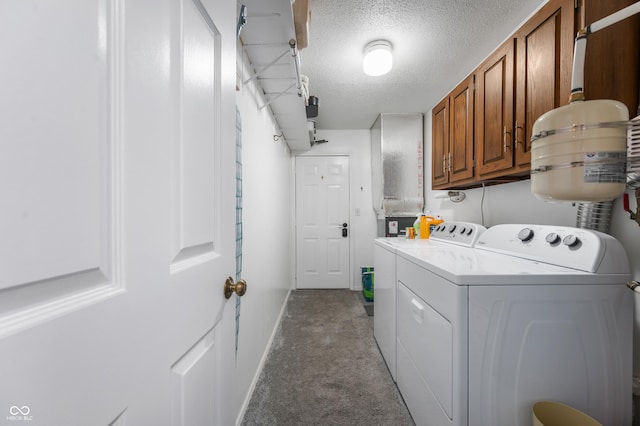 clothes washing area with a textured ceiling, baseboards, cabinet space, light carpet, and washer and dryer