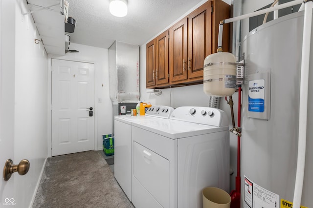 washroom with baseboards, washing machine and clothes dryer, cabinet space, water heater, and a textured ceiling