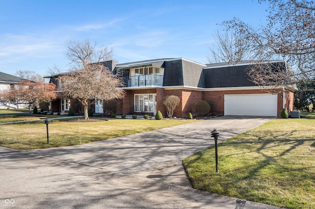 view of front facade featuring a front lawn, mansard roof, concrete driveway, a balcony, and brick siding