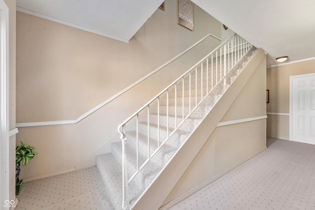 staircase featuring ornamental molding and carpet flooring