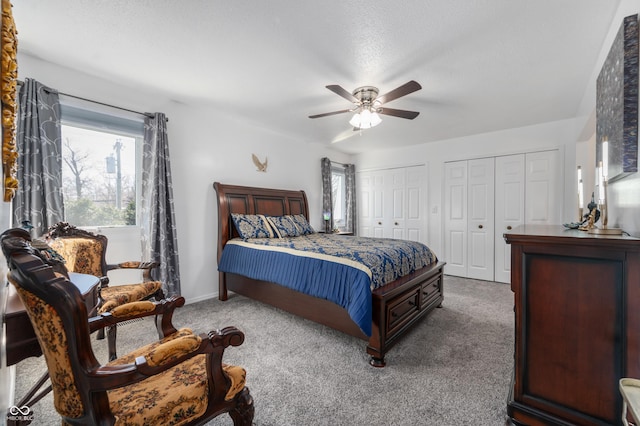 carpeted bedroom featuring a ceiling fan, baseboards, and two closets