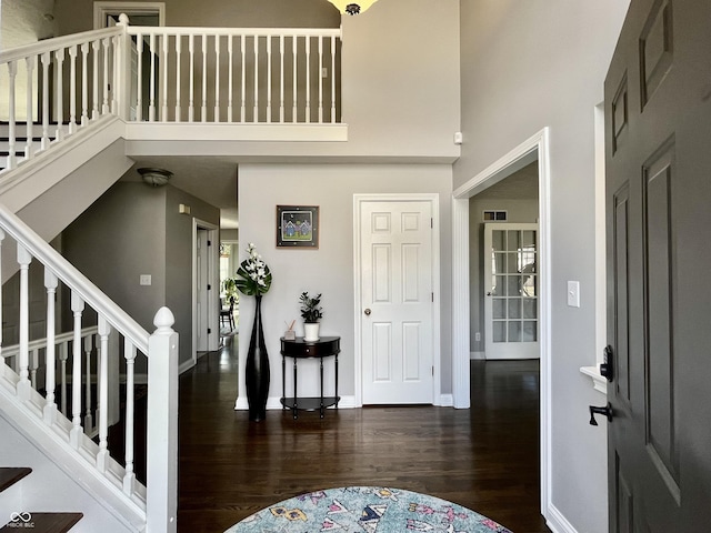 entryway featuring visible vents, wood finished floors, stairway, a high ceiling, and baseboards