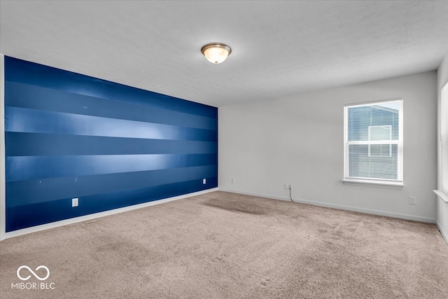 empty room featuring baseboards, carpet floors, and a textured ceiling