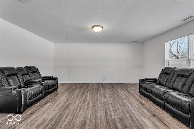 living room featuring visible vents, baseboards, a textured ceiling, and wood finished floors