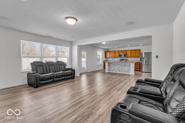 living area featuring light wood-style flooring, recessed lighting, baseboards, and a textured ceiling