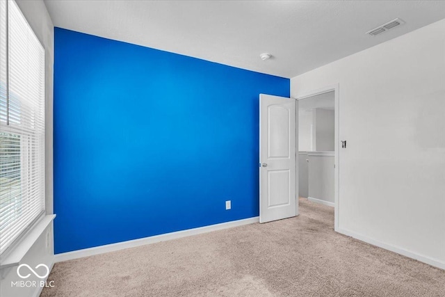 carpeted spare room with visible vents and baseboards