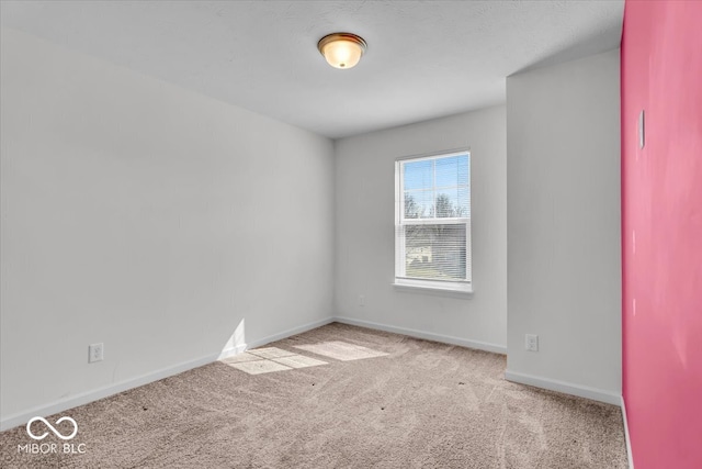 carpeted spare room featuring baseboards