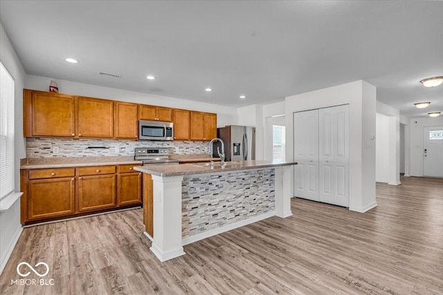 kitchen featuring brown cabinets, stainless steel appliances, light wood-type flooring, and a sink