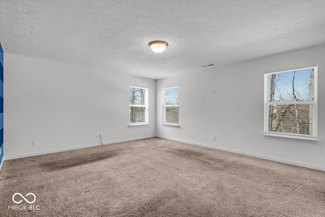 carpeted empty room with visible vents, baseboards, and a textured ceiling