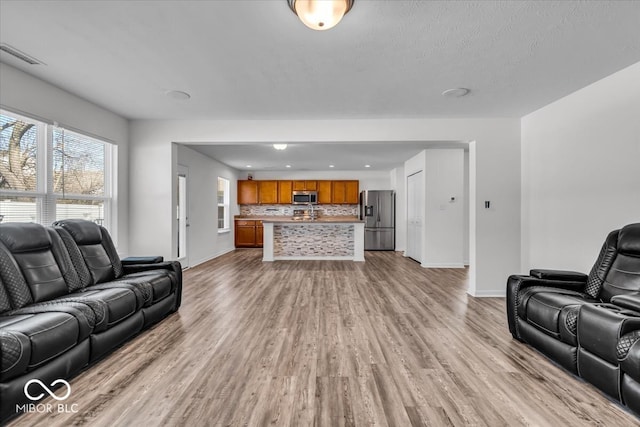 living room with visible vents, baseboards, and light wood-style flooring