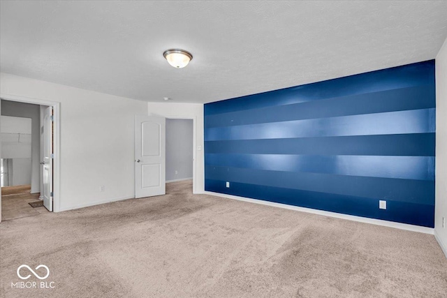 carpeted empty room featuring baseboards and a textured ceiling