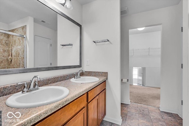 bathroom featuring double vanity, visible vents, tiled shower, and a sink