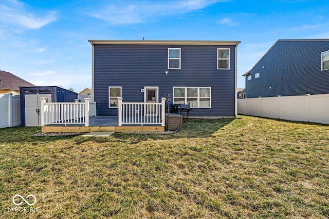 rear view of house with a wooden deck, a lawn, and fence