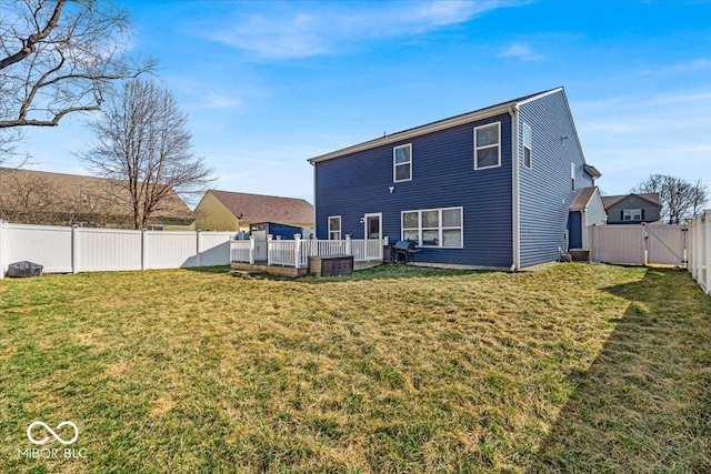 rear view of house with a gate, a fenced backyard, a yard, and a wooden deck