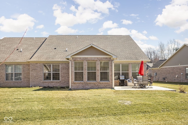 rear view of property with brick siding, a lawn, a patio, and roof with shingles