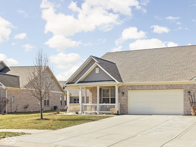 view of front of house featuring a front lawn, covered porch, concrete driveway, a garage, and brick siding