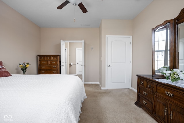 bedroom featuring visible vents, baseboards, ceiling fan, light colored carpet, and ensuite bath