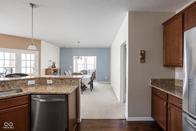 kitchen featuring decorative light fixtures, baseboards, stainless steel appliances, and light stone counters