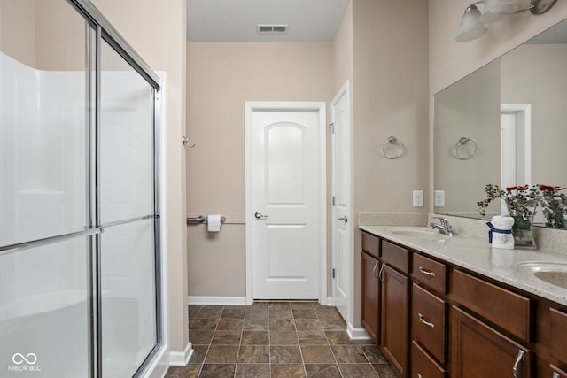 bathroom featuring double vanity, visible vents, a shower stall, and a sink