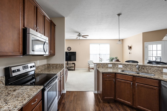 kitchen with dark wood finished floors, a sink, stainless steel appliances, pendant lighting, and a textured ceiling