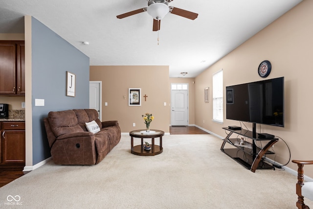 carpeted living room featuring baseboards and ceiling fan