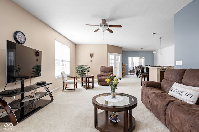 living area featuring light colored carpet, a ceiling fan, and baseboards