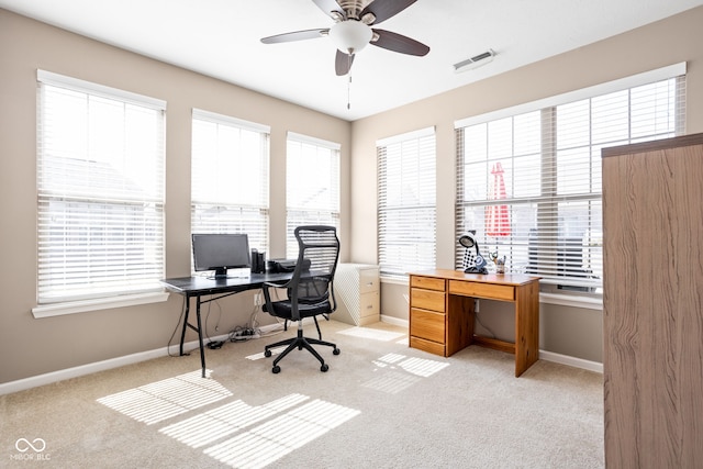 office area featuring plenty of natural light, baseboards, visible vents, and light carpet