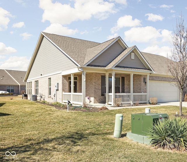 view of front of house with a front yard, covered porch, a shingled roof, a garage, and brick siding