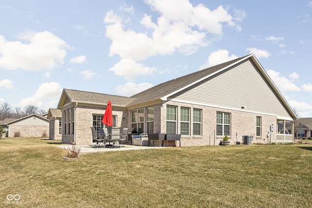 rear view of property with brick siding, a patio area, and a yard