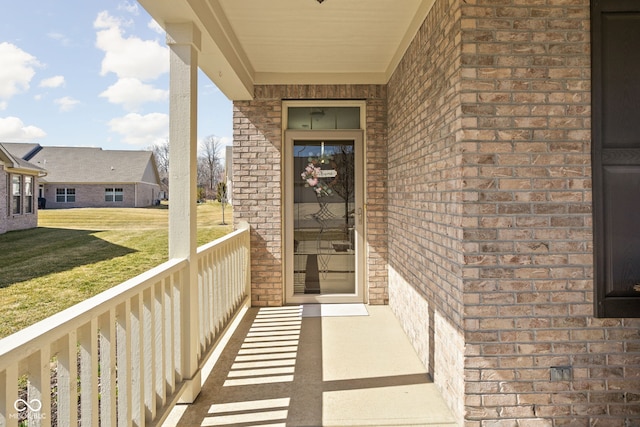 view of exterior entry with brick siding and a lawn