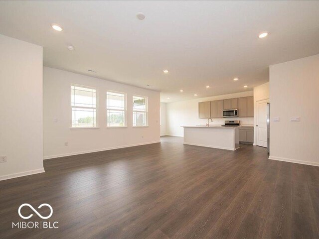 2254 Oakmont Dr, Plainfield, IN 46168 - unfurnished living room featuring dark wood-style flooring, recessed lighting, baseboards, and a sink