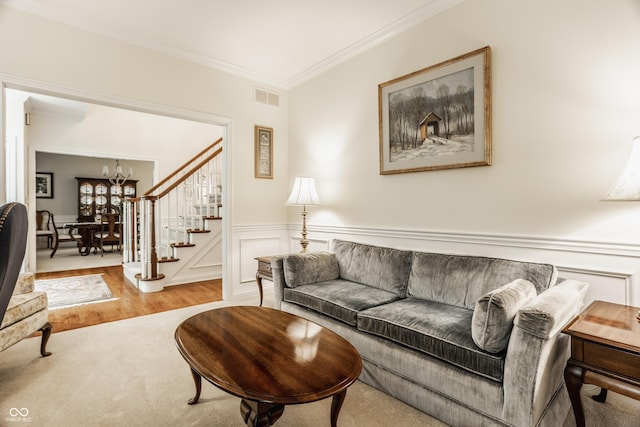 living room featuring visible vents, a wainscoted wall, ornamental molding, a chandelier, and stairs