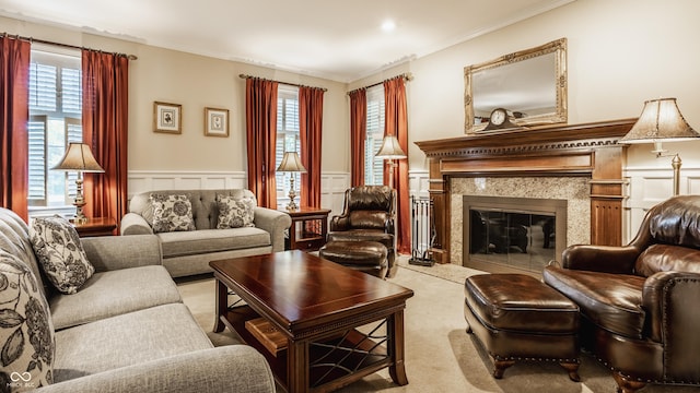 carpeted living room with plenty of natural light, wainscoting, a fireplace, and crown molding