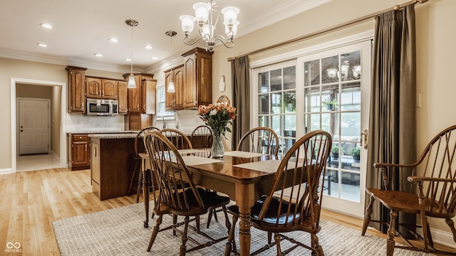 dining space with baseboards, an inviting chandelier, recessed lighting, crown molding, and light wood-type flooring