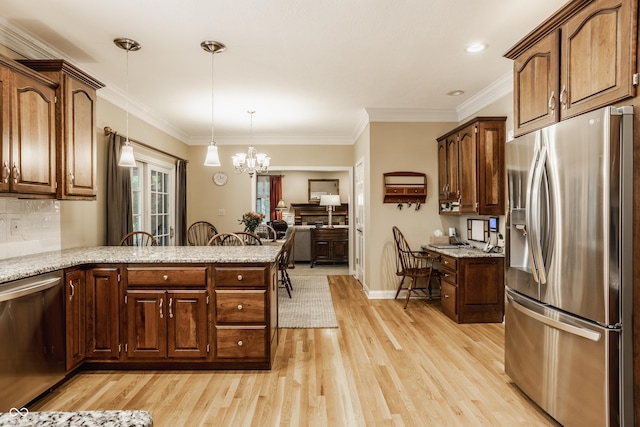 kitchen featuring decorative light fixtures, stainless steel appliances, a peninsula, light wood finished floors, and a chandelier