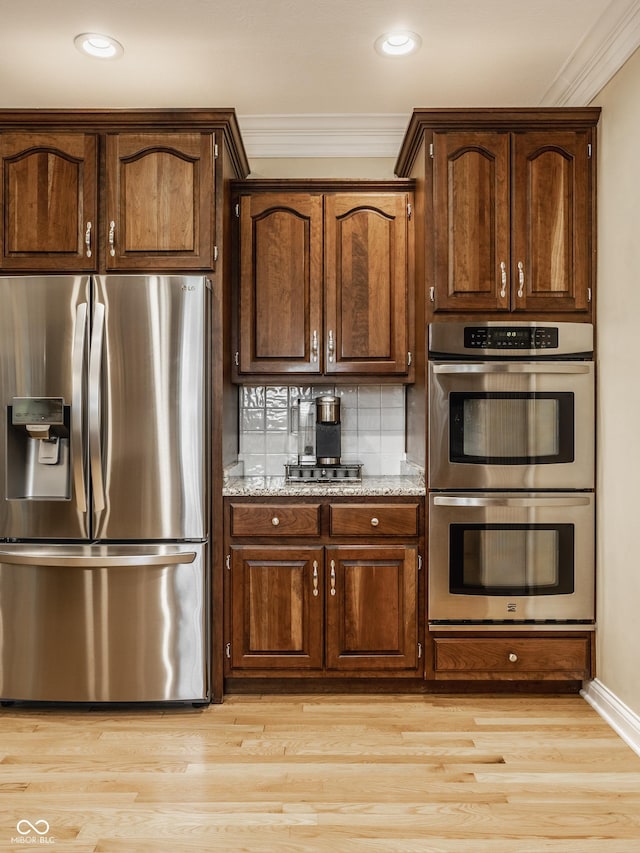 kitchen with ornamental molding, tasteful backsplash, appliances with stainless steel finishes, light wood finished floors, and dark brown cabinets