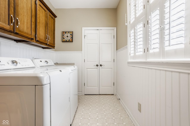 laundry area featuring cabinet space, independent washer and dryer, light floors, and wainscoting