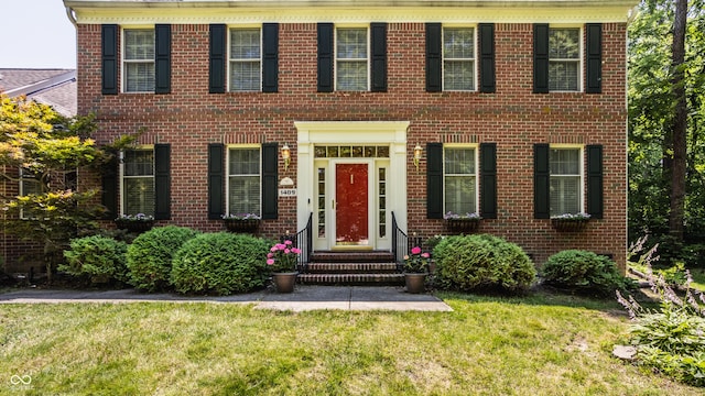 view of front of property featuring entry steps, a front yard, and brick siding