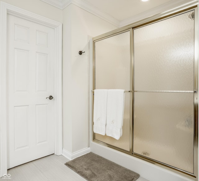 bathroom with a shower with door, crown molding, and baseboards