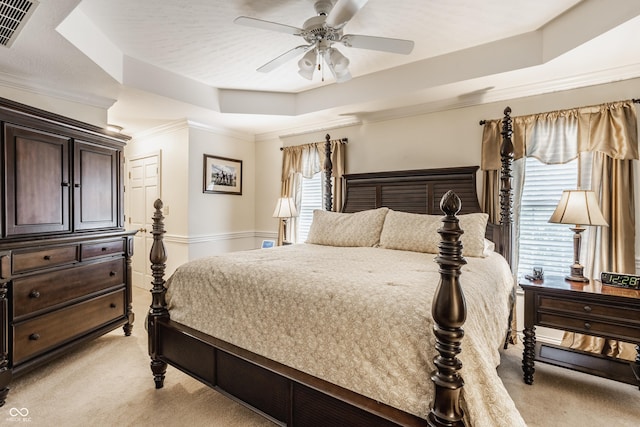 bedroom with visible vents, light colored carpet, a raised ceiling, and multiple windows