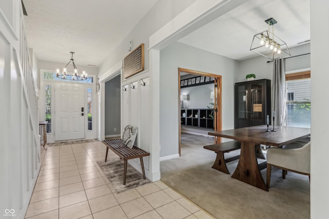 entrance foyer featuring light colored carpet, light tile patterned flooring, a notable chandelier, and a healthy amount of sunlight