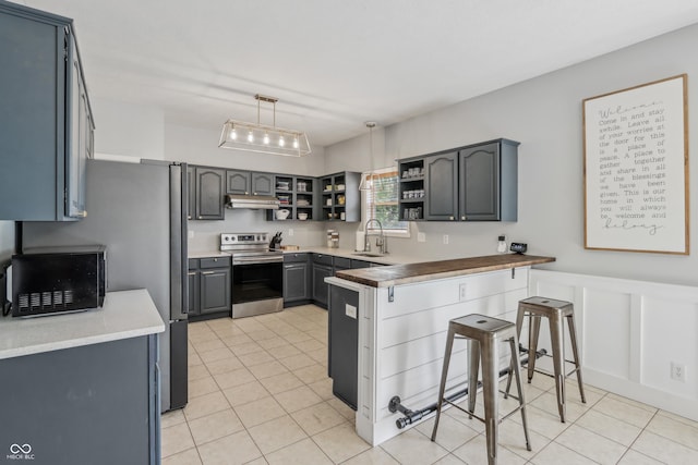 kitchen featuring open shelves, under cabinet range hood, a sink, light tile patterned floors, and stainless steel appliances