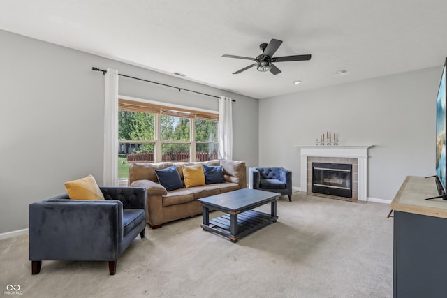 living area featuring a ceiling fan, baseboards, light colored carpet, and a tiled fireplace