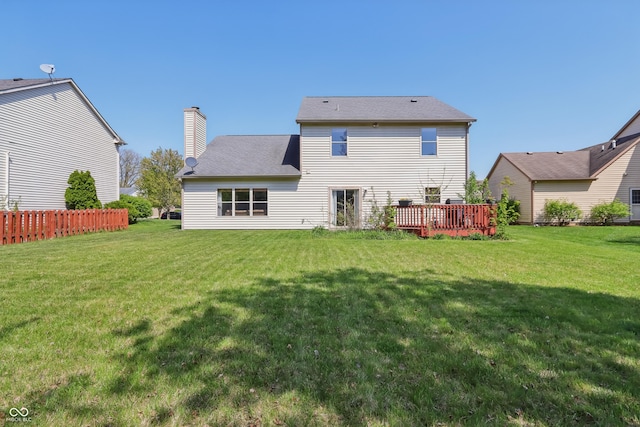 rear view of house featuring a lawn, a deck, fence, and a chimney