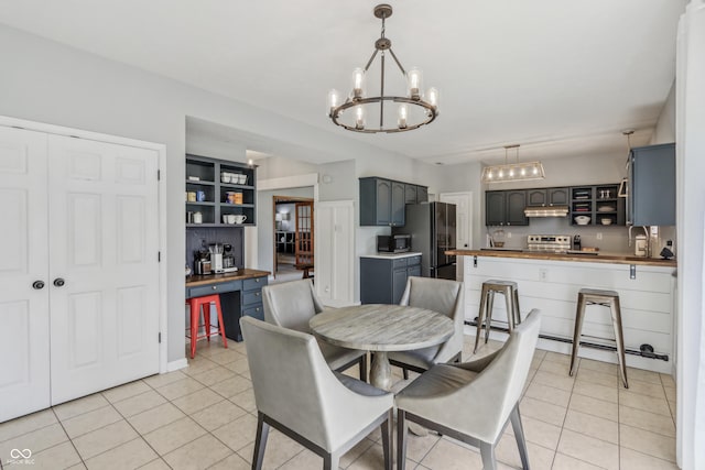 dining room with light tile patterned flooring, a chandelier, built in shelves, and baseboard heating