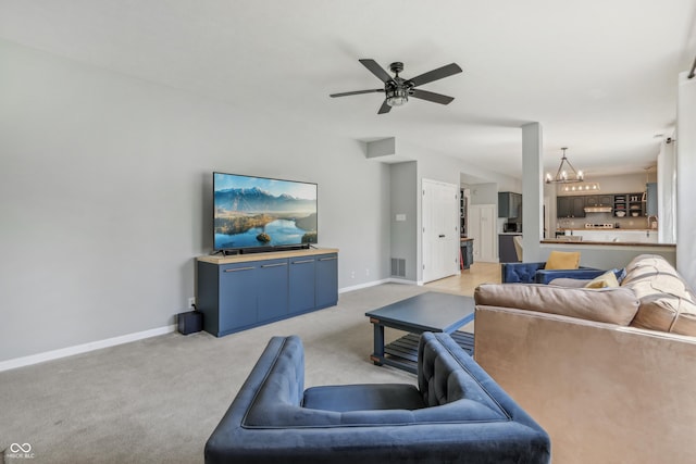 living room with baseboards, visible vents, light carpet, and ceiling fan with notable chandelier